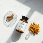 Vita Elixia KSM-66 Ashwagandha supplement bottle on marble with dried ashwagandha roots and sliced turmeric.