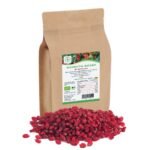 Ein 500g Standbeutel von Blumental Bayern Bio-Berberitzen aus braunem Kraftpapier, der hinter einem Haufen leuchtender, ganzer getrockneter roter Berberitzen gezeigt wird